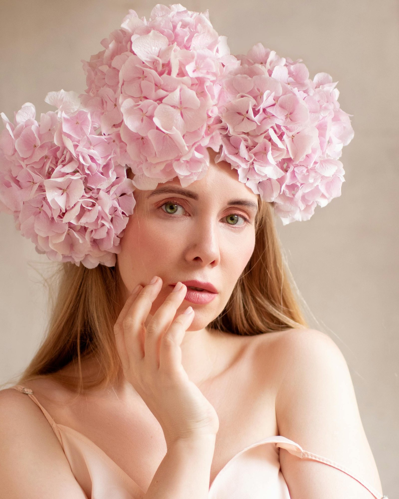 A stunning studio portrait of a healthy woman wearing a pink hydrangea flower headdress.